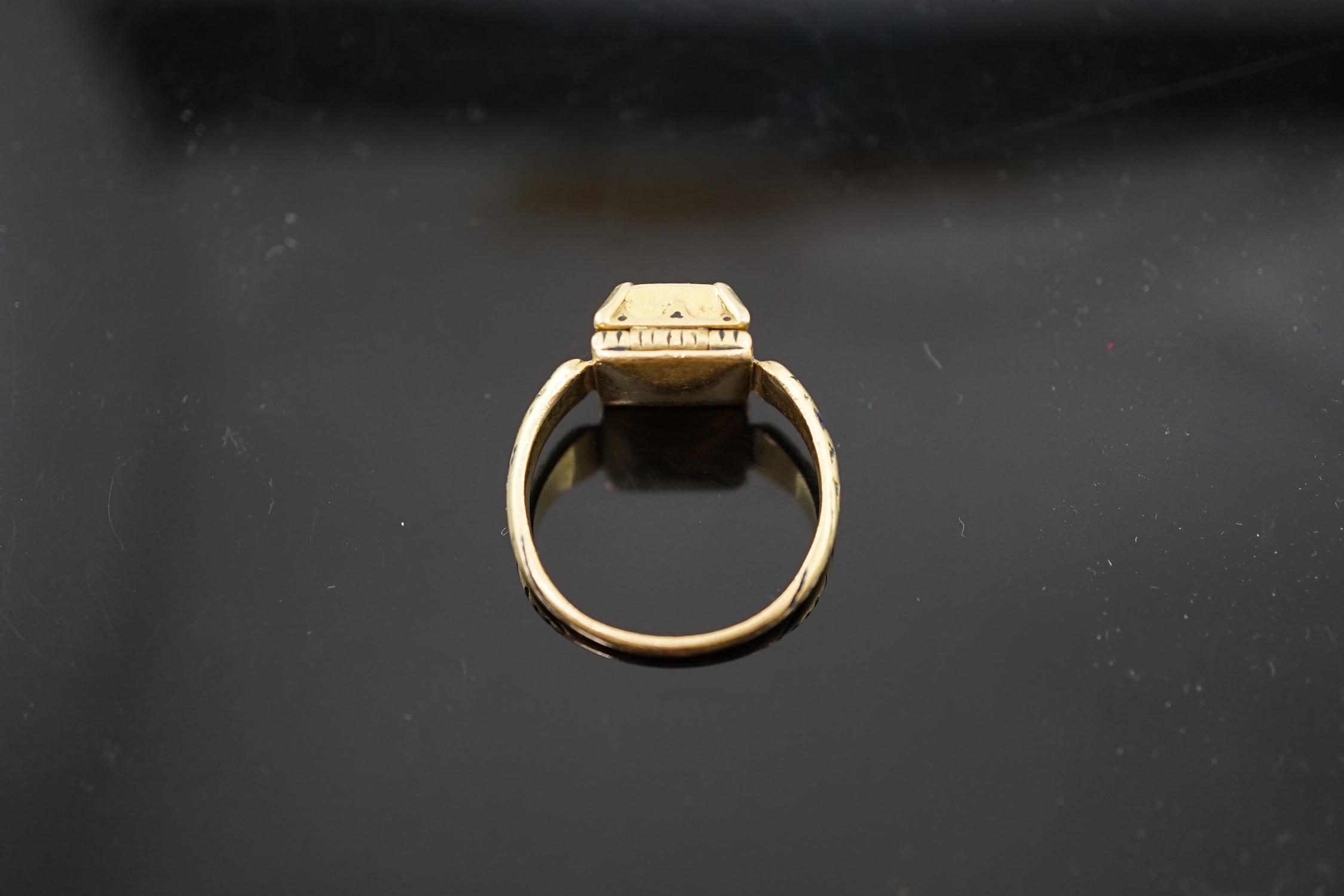 An antique high carat gold, black enamel and collet set cushion cut sapphire set 'poison' ring